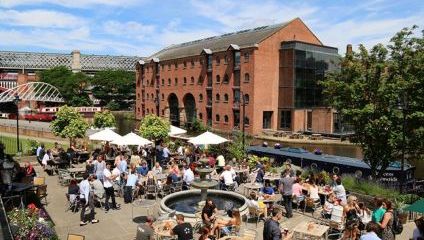 Crowded Outside terrace of the pub on a summers day looking over the canal and a warehouse apartment building in the background