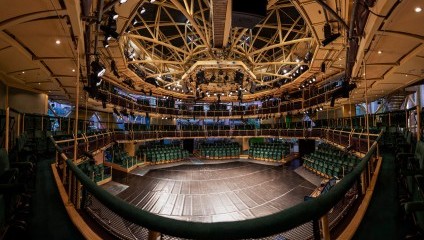 Inside the an old Corn Exchange is a metal scaffold built round theatre. Rows of green seats, a stage and many lights over the main stage