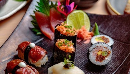 4 different types of sushi including tuna and white fish laid on an oblong wooden plate with green garnsih