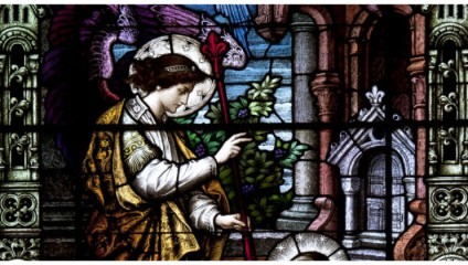 A colorful stained glass window depicting a serene saintly figure in medieval attire, holding a red staff. Behind, architectural details of a cathedral and a dragon are visible. The scene features rich hues and intricate designs, representing a religious motif.