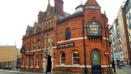 Outside the front of the Kings Arms. Victorian facade with red brick and pub sign.