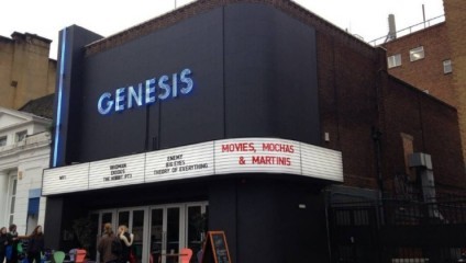 A brick building with a marquee sign shows MOVIES, MOCHAS & MARTINIS and various film titles. The building, named GENESIS, has a boxy, modern design. People are gathered at the entrance, and there's a seating area with red and blue chairs outside.