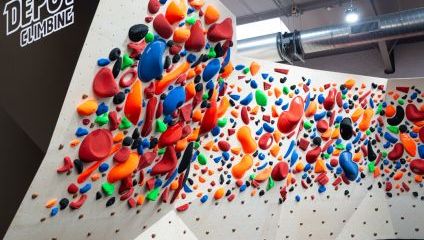 white climbing wall with hundreds of multi coloured shapes for climbing on