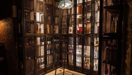 Alcohol bottles behind a black cage and backlit