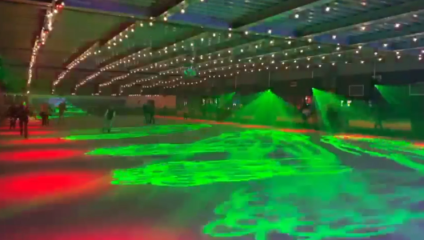 Under low light, the ice rink at QUEENS London is bathed in red and green