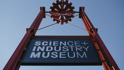 Science + Industry museum sign on a tall red piece of ironwork