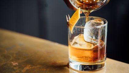 Whisky sour being poured into a glass on a bar