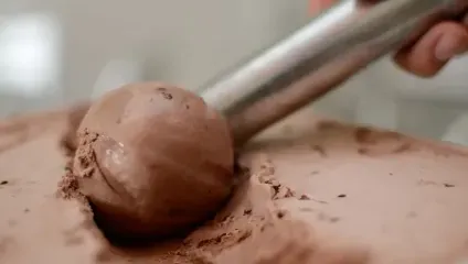 Chocolate icecream being scooped out with metal scooper