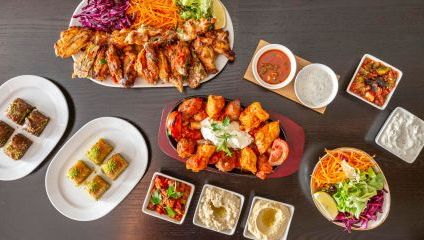 Lots of colourful Turkish dishes - dips, meat, salad on a wooden table