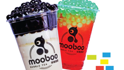 Two bubble tea drinks in plastic cups with the mooboo logo. The left drink has black tapioca pearls and a white base, while the right drink has green tapioca pearls and a red base. Four small colored squares are at the bottom right.