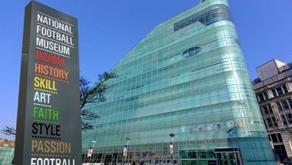 Outside the all glass museum. Large sign saying National Football Museum, Drame, history, skill, art, faith, style, passion, football