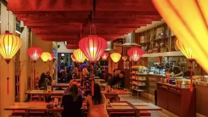 Inside the restaurant, red lighting, lanterns, tables and chairs, people eating
