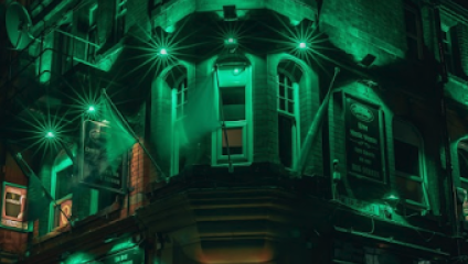 Outside facade of Victorian pub in the dark and lit-up green