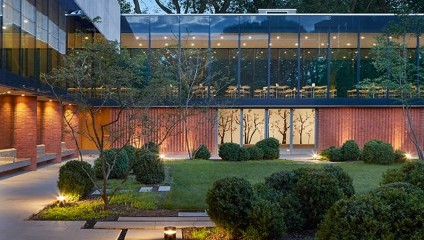 The front of the Whitworth art gallery showing a glass-walled cafe space overlooking the green garden