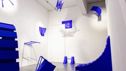 Blue installations stuck to the gallery walls of a white room