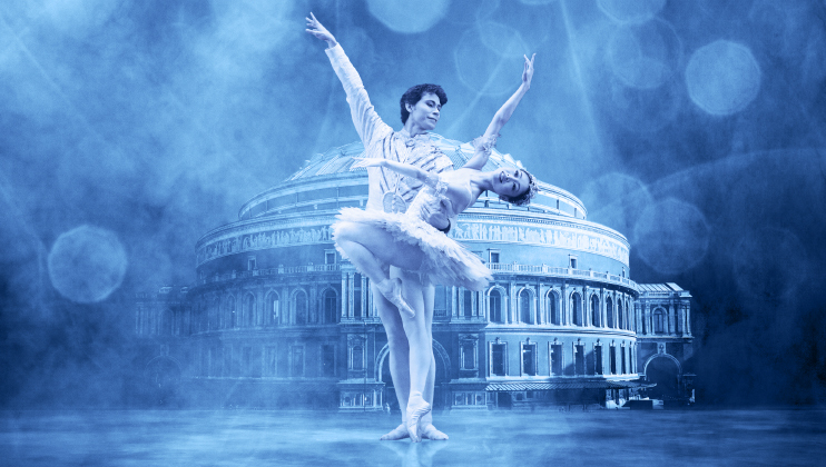 A ballet dancer lifts his partner during a performance, set against a blue-toned background with bokeh effects. They are in front of a large, ornate building with a circular dome, possibly a theater. Both dancers wear traditional ballet attire, with the woman in a tutu.