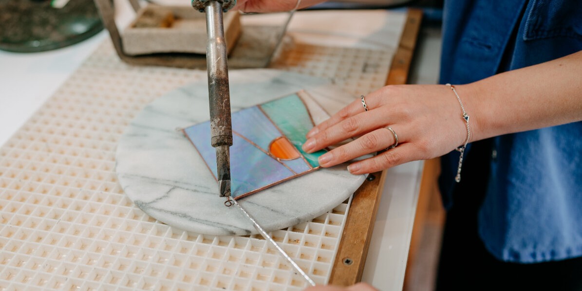 A close up of the stained glass making process in a bright, airy workshop.