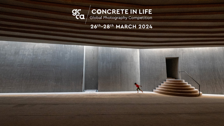 A young child in red is running across a large, modern, concrete interior with stepped seating leading to a door. The ceiling has layered, curved designs. Text at the top reads Concrete In Life Global Photography Competition and 26th-28th March 2024.