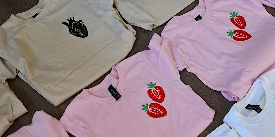 Colourful handmade T-shirts featuring lino-printed designs of strawberries and anatomical hearts, promoting a creative lino print workshop where participants can design and print their own clothing.