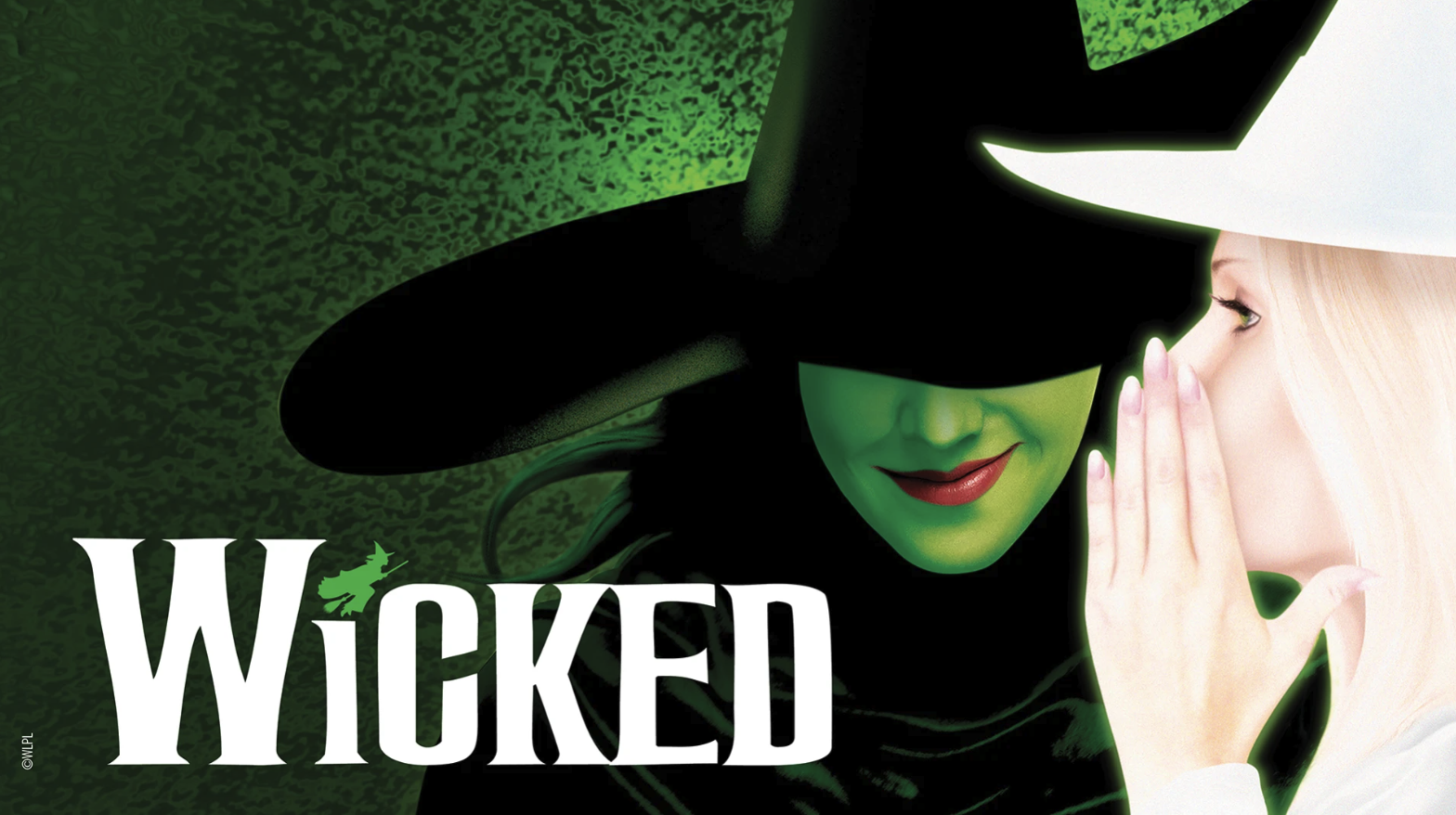 A promotional image for the musical Wicked shows a green-faced figure in a black hat smiling, while a fair-skinned figure wearing a white hat whispers in their ear. The word Wicked appears in bold white letters at the bottom.
