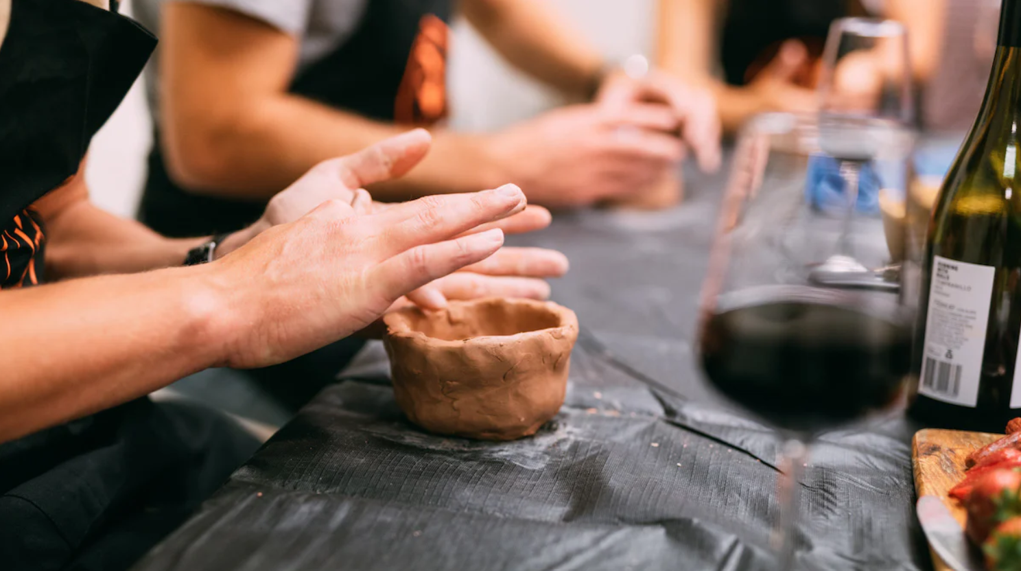 Close up of hands sculpting air-dry clay with a glass of wine handy nearby.
