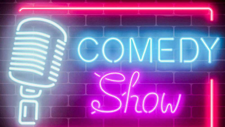 A neon sign on a brick wall background displays a large microphone on the left and the words COMEDY Show in bright blue and pink glowing letters. The sign creates a vibrant and inviting atmosphere.