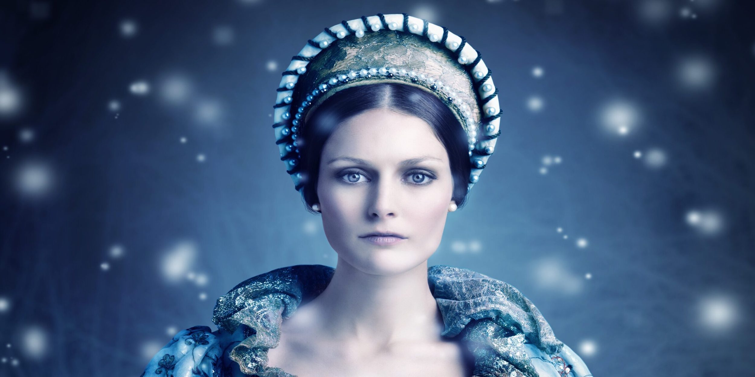 A woman with an elegant, pearl-adorned headdress and intricate blue and silver attire faces the camera. Her expression is serene, and she is surrounded by a dreamy, snowy, and ethereal background with glowing specks of light.