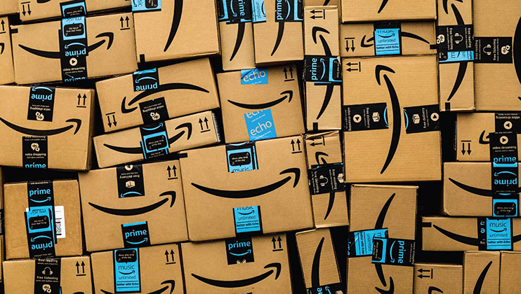 A large number of stacked Amazon delivery boxes with various Amazon-branded tapes, including Prime and Echo labels. The boxes are piled haphazardly, creating a chaotic and dense arrangement of cardboard packages.