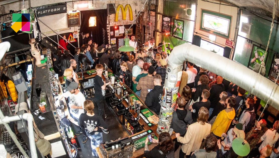 Shot from a mezzanine area a crowd of people watch a band performing in one of the many live music venues in Brighton