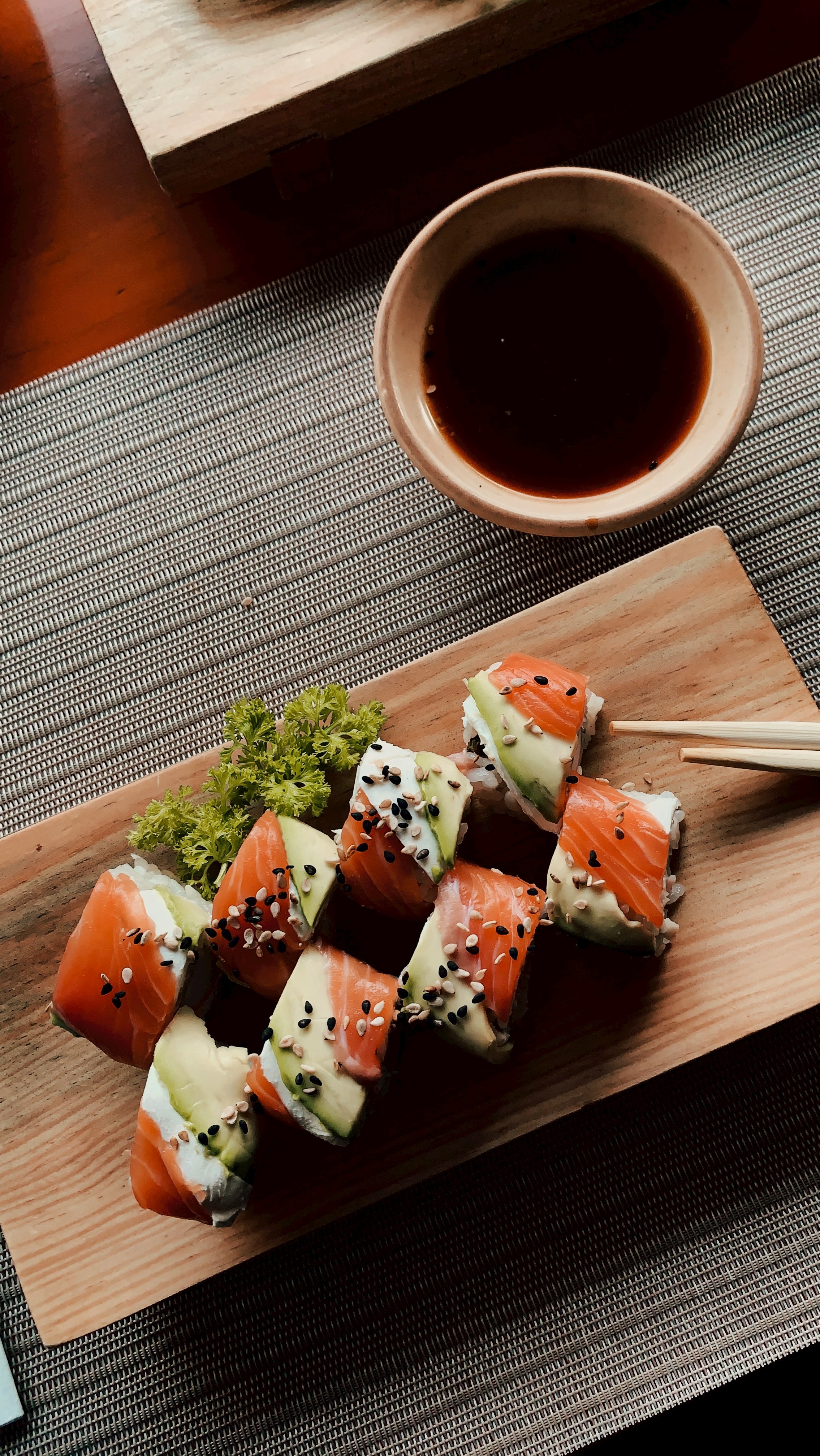 Plate of sushi rolls with salmon and avocado with black sesame seeds scattered on top