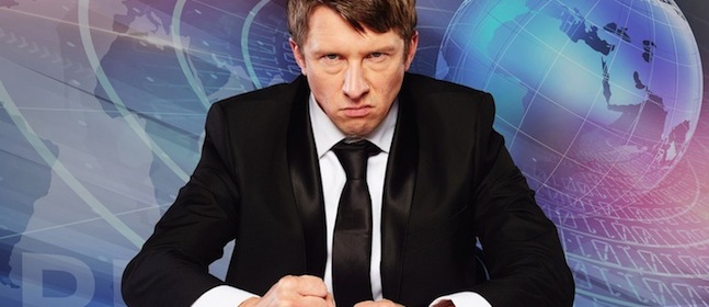 A person wearing a black suit and black tie is seated with hands clenched into fists on a desk, displaying a serious expression. The background features abstract digital imagery, including a globe and various technological and data-related graphics.