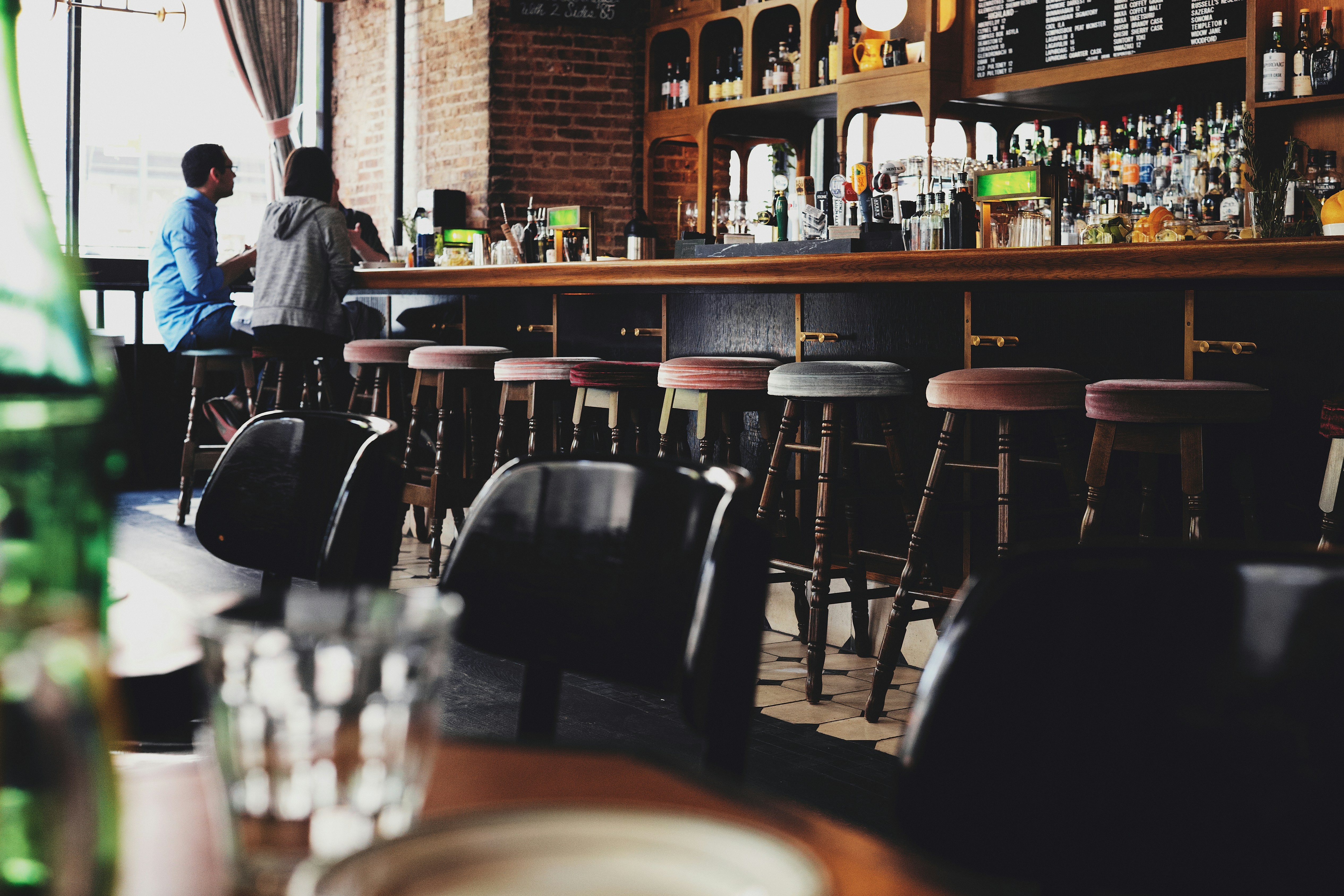 Inside a British pub, wooden bar, stools and 2 man talking at the bar