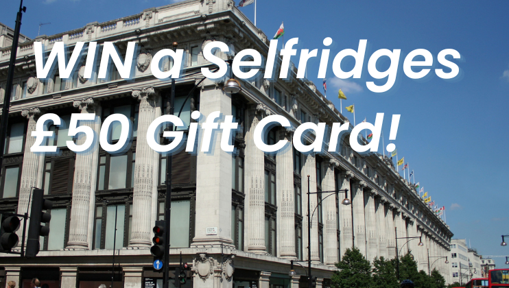 Exterior view of a Selfridges store with text overlay advertising a contest to win a £50 gift card. The building features classical architecture with columns and multiple large windows, adorned with flags on the roof. The sky is clear and blue.